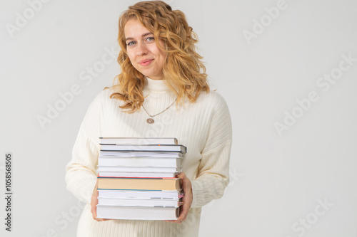 Cute young blonde girl with books in her hands, white background, copyspace