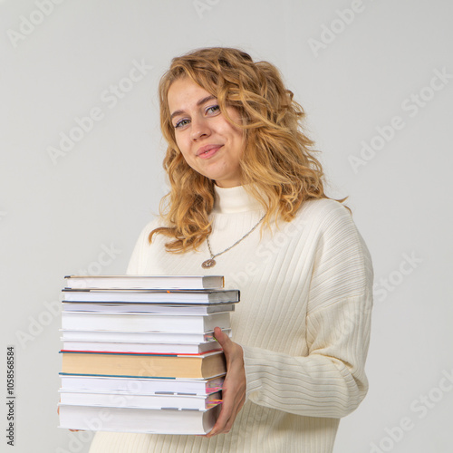 Cute young blonde girl with books in her hands, white background, copyspace