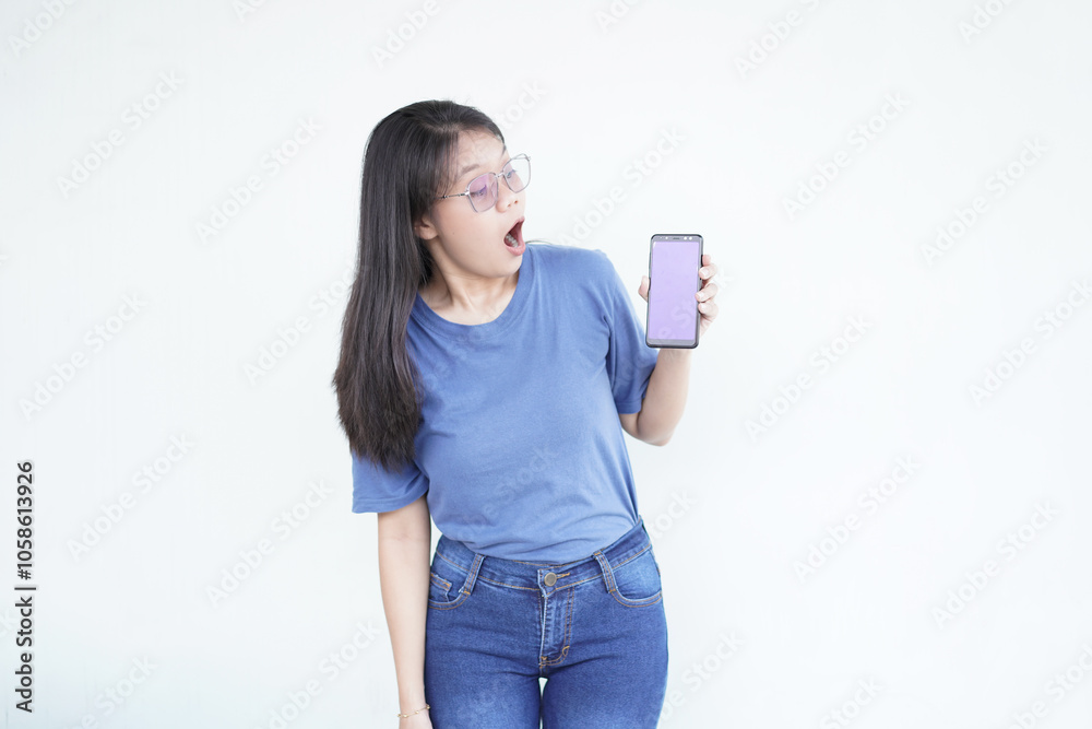 beautiful Asian woman displays a shocked expression while holding up her smartphone against a white background beautiful Asian woman displays a shocked expression while holding up her smartphone against a white background