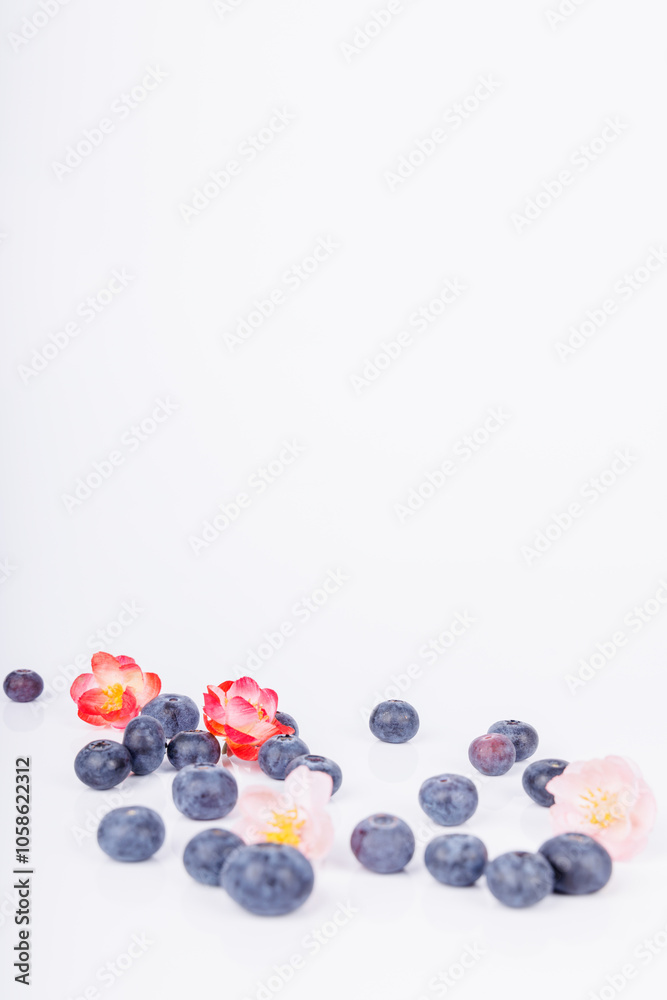 Blueberries and colorful flowers scattered on a white surface, showcasing a beautiful blend of nature’s colors and textures in a simple composition