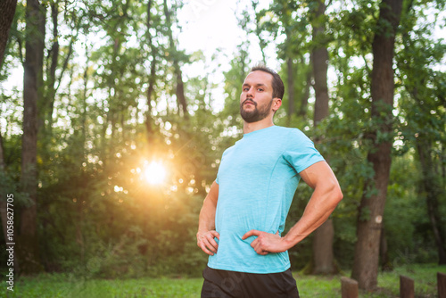 Athlete posing with hands on hips in nature