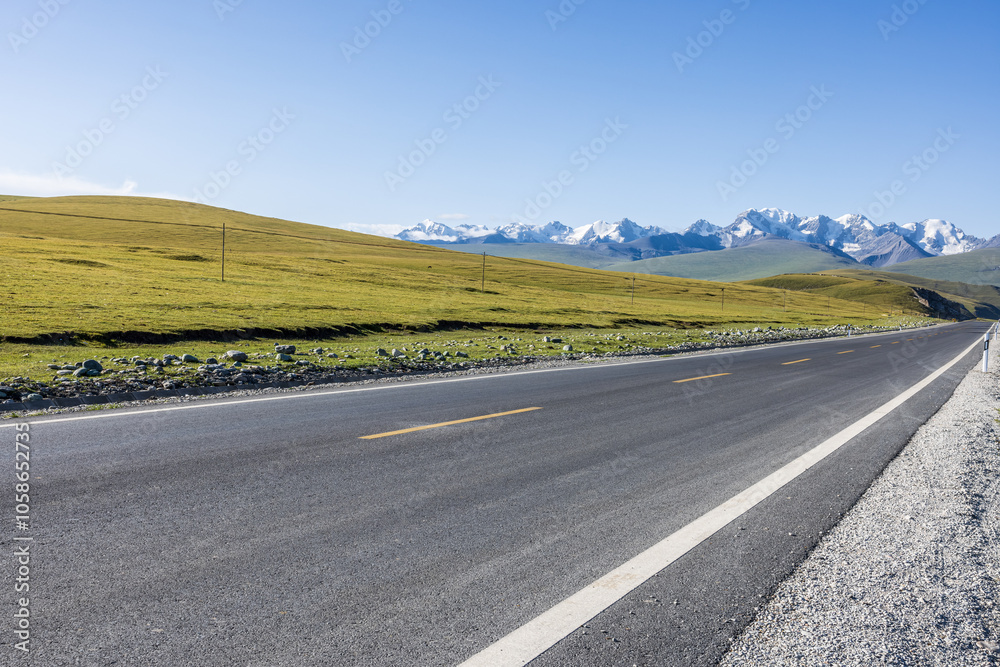 Asphalt highway road and green grass with snow mountain natural landscape under blue sky. road trip. Asphalt highway road and green grass with snow mountain natural landscape under blue sky. road trip.
