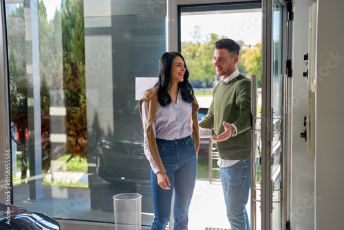 A smiling couple engaged in conversation entrance at the modern car saloon.