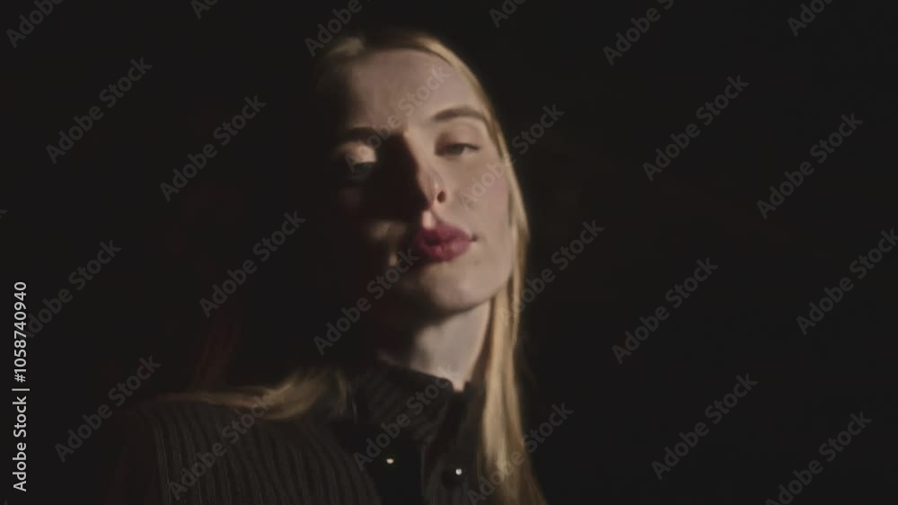 Model changing poses while a photographer adjusts lighting during a fashion shoot creates a dynamic atmosphere. The interplay of light and shadows enhances the elegance and style of the session