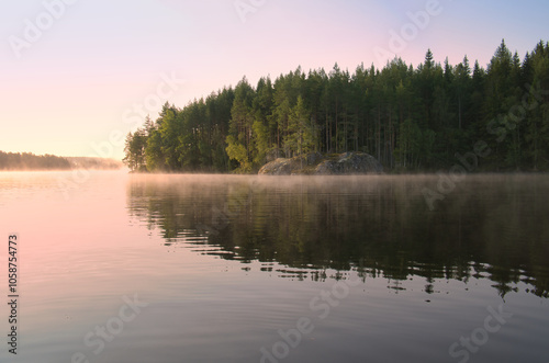 Lake in Sweden at sunrise with romantic light, blue water and trees on the shore