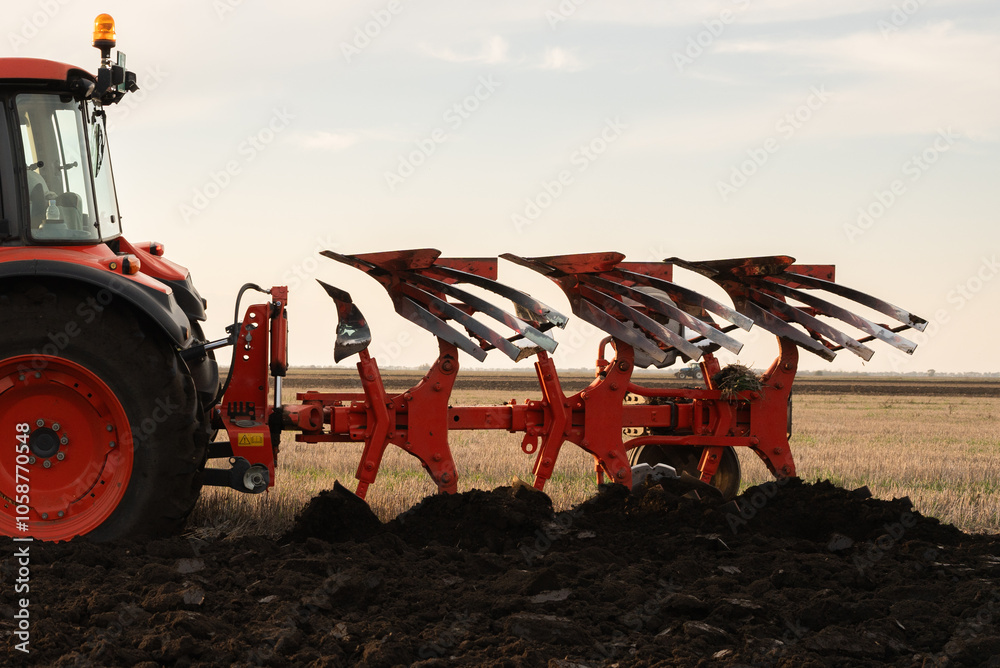 Obraz premium Tractor on the field during sunset.