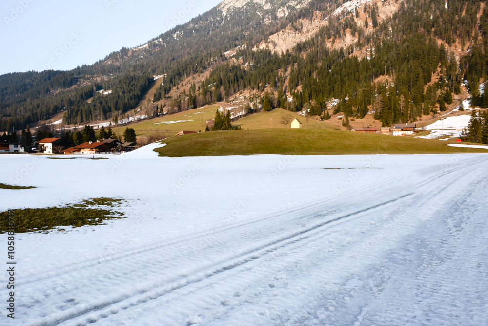 Snowy road across the field in perspective to a winter resort village with a ski resort. Picturesque winter landscape Snowy road across the field in perspective to a winter resort village with a ski resort. Picturesque winter landscape