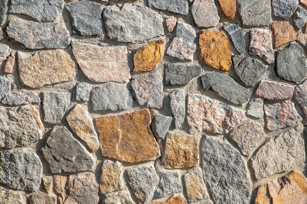 Sunny stone wall made of natural granite, close-up texture of stone masonry Sunny stone wall made of natural granite, close-up texture of stone masonry