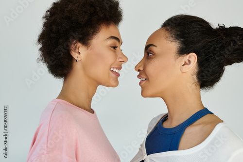 Two women stand face to face, radiating warmth and happiness in a calm setting.