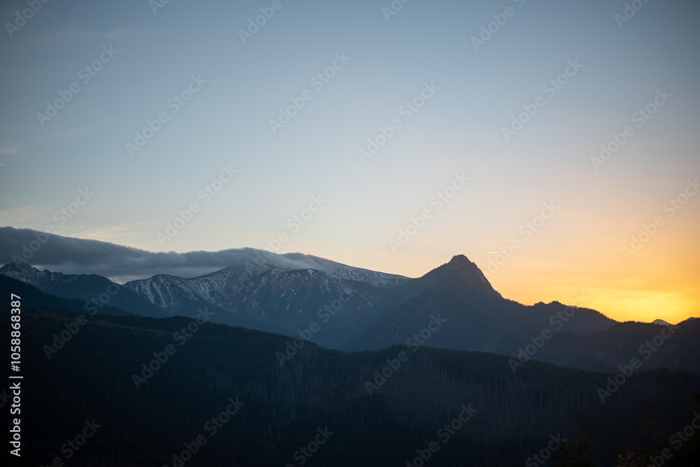 Obraz premium The sunset atop Mount Kopieniec in Zakopane, Poland, casts a warm glow over the Tatra Mountains, creating a stunning landscape