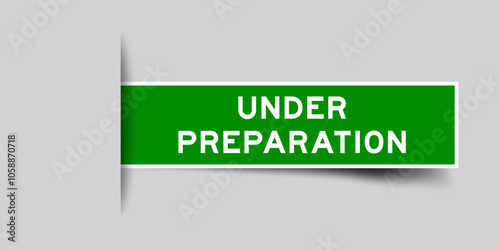 Green color square label sticker with word under preparation that inserted in gray background