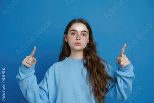 A young woman with an artistic and unique makeup look, posing with confidence.