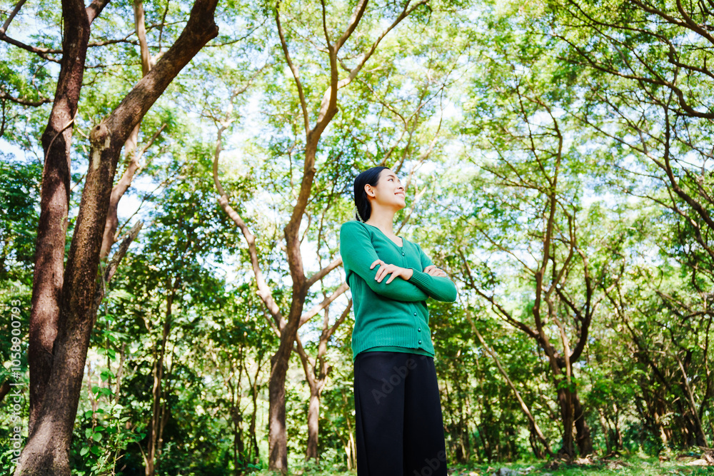 Young Asian woman sits under a shady tree in a park, enjoying her free time in nature. She breathes deeply, refreshing herself, surrounded by leaves and the tranquility of greenery. Young Asian woman sits under a shady tree in a park, enjoying her free time in nature. She breathes deeply, refreshing herself, surrounded by leaves and the tranquility of greenery.