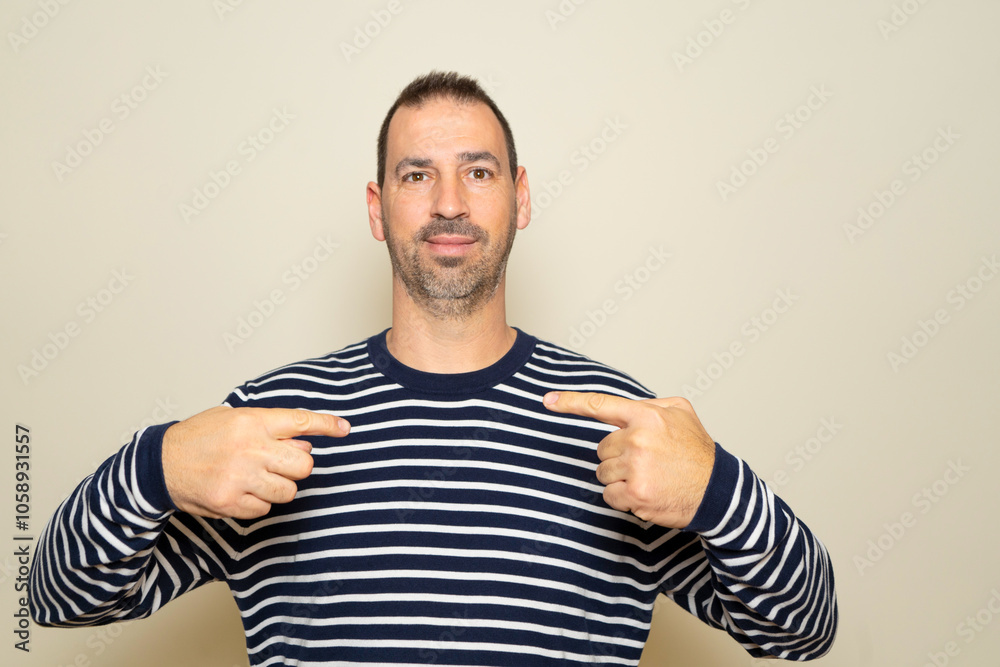 Bearded Hispanic man in his 40s wearing a striped sweater pointing at himself proud of the job he just did. Bearded Hispanic man in his 40s wearing a striped sweater pointing at himself proud of the job he just did.