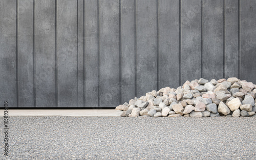 Piled stones in front of a textured gray wall showcasing modern landscaping design elements photo