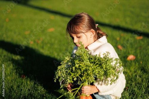 little girl farmer with vegetables and pumpkin on the background of green grass and vegetable garden. healthy eating concept.