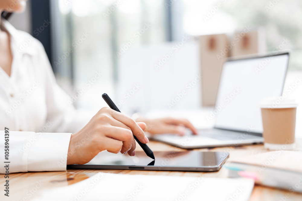 Fototapeta premium Businesswoman using stylus pen signing contract on digital tablet working on laptop computer in modern office, electronic signature. Business man taking note