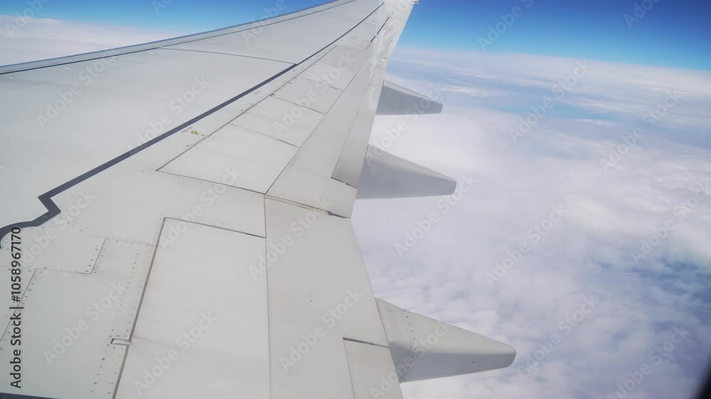 Plane Gracefully Flies Above Blanket of Clouds, Showcasing Wing and Expansive Blue Sky on Clear Day. Wing of airplane soaring high above clouds Plane Gracefully Flies Above Blanket of Clouds, Showcasing Wing and Expansive Blue Sky on Clear Day. Wing of airplane soaring high above clouds
