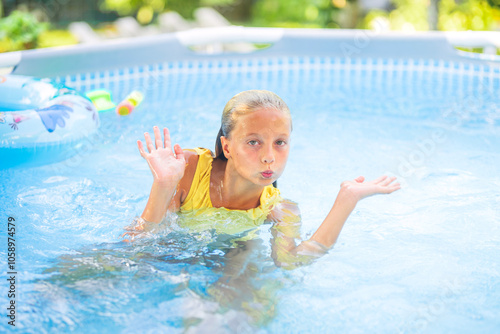 Girl making funny face is playing in swimming pool photo