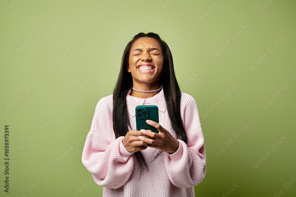 The young woman smiles brightly while engaging with her phone in warm autumn style. The young woman smiles brightly while engaging with her phone in warm autumn style.