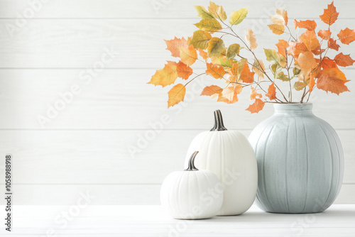 serene autumn arrangement featuring white pumpkins and blue vase with orange leaves, evoking cozy seasonal atmosphere