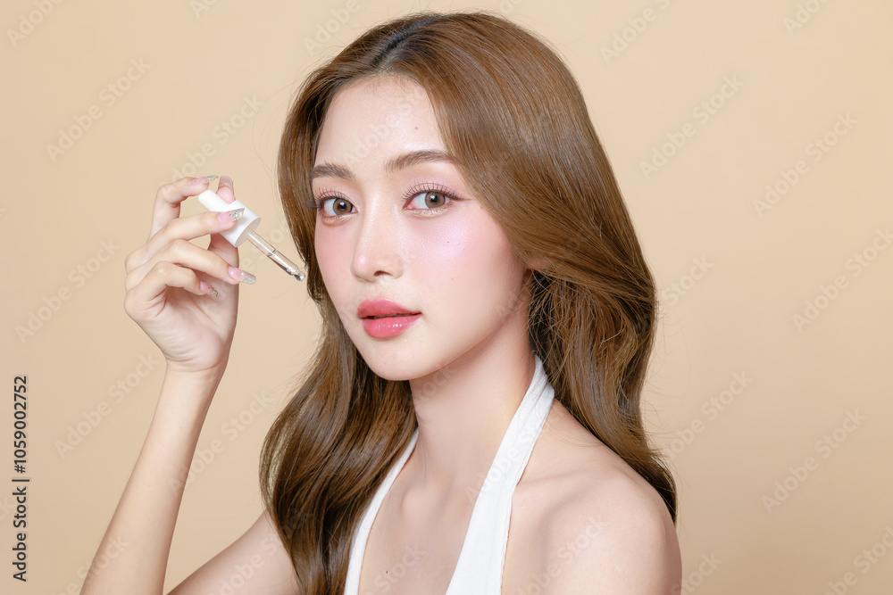 Young Asian beauty woman curly long hair with korean makeup style on face and using pipette to apply serum on skin on isolated beige background. Facial treatment, Cosmetology, plastic surgery. Young Asian beauty woman curly long hair with korean makeup style on face and using pipette to apply serum on skin on isolated beige background. Facial treatment, Cosmetology, plastic surgery.