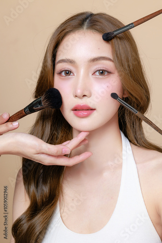 Young Asian beauty woman curly long hair with korean makeup style touch her face and perfect skin on isolated beige background. Facial treatment, Cosmetology, plastic surgery.