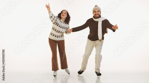 Cheerful stylish couple in cozy and warm winter outfits ice skating together, having fun and joy during winter vacation. isolated on white background. Concept of winter, holiday, leisure activity
