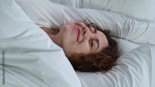 Young woman sleeping in bed. Portrait of a beautiful woman resting on a comfortable bed with pillows in white bedding in the bedroom in the morning. High quality image.