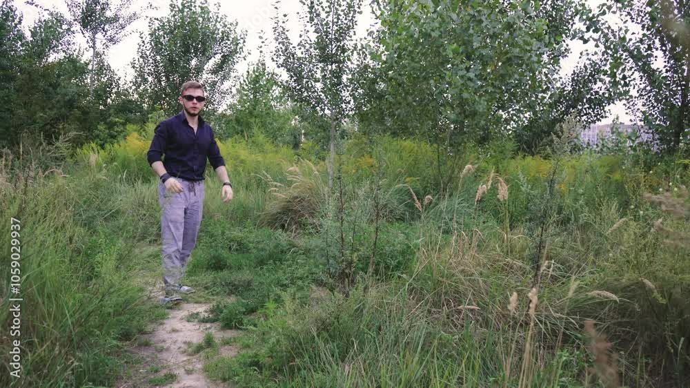 Back view of a young man leisurely strolling through the urban area surrounded by greenery. Suitable for lifestyle and outdoor scenes. Back view of a young man leisurely strolling through the urban area surrounded by greenery. Suitable for lifestyle and outdoor scenes.