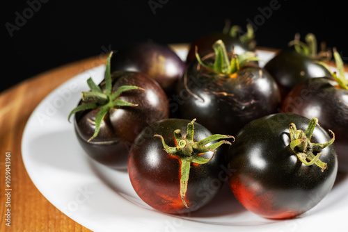 Cumato black tomatoes in a white plate. Black tomato. photo