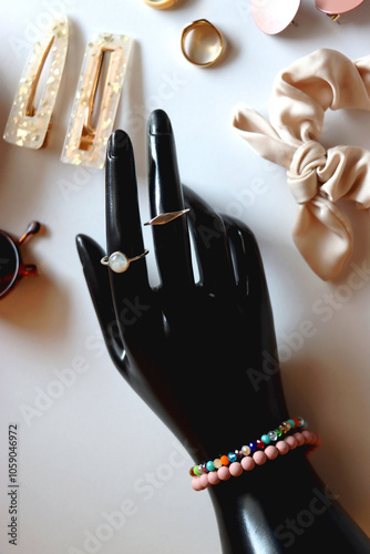 Obraz na płótnie Hand figurine, sunglasses, gold jewelry, colorful bead jewelry, statement rings and various hair accessories on the white table. Flat lay. w salonie
