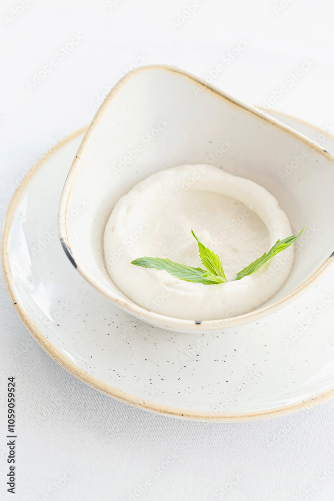 A small bowl of garlic dip topped with herb. A small bowl of garlic dip topped with herb.