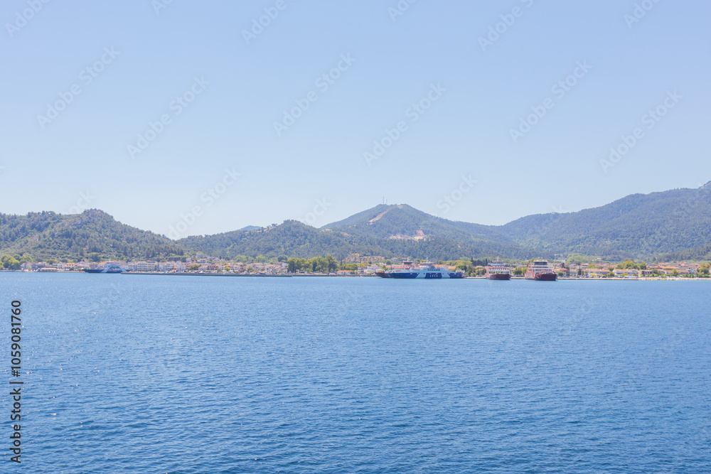 Ferry port at Thasos Island, Greece, with ferries docked and scenic mountain views in the background Ferry port at Thasos Island, Greece, with ferries docked and scenic mountain views in the background