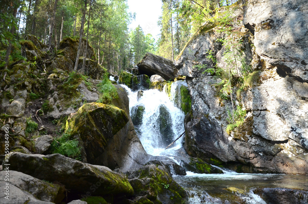 Waterfall flows from a height over rocks, mountain river