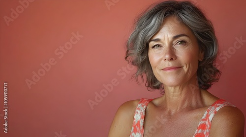 A full body shot of a mature Australian woman who appears relaxed and comfortable in a casual sundress posing in a lighting studio against a plain amaranth background