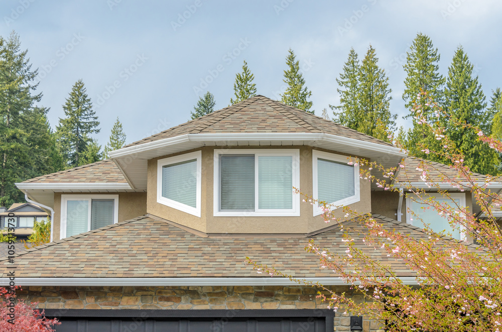 Fototapeta premium Top of grey stucco luxury house with shingle roof, red and yellow trees and nice windows in Summer in Vancouver, Canada, North America. Day time on June 2024.