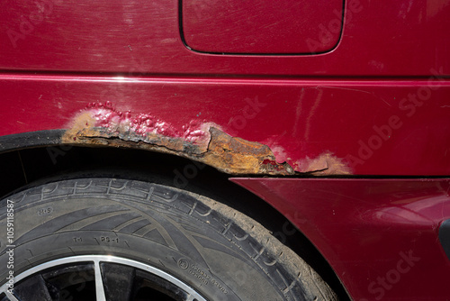 Rusty car. Red old rusty car. Fragment of a red wing of an old car. Rusty hole in metal