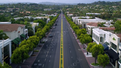 Aerial view of a long, straight road lined with shops and trees.