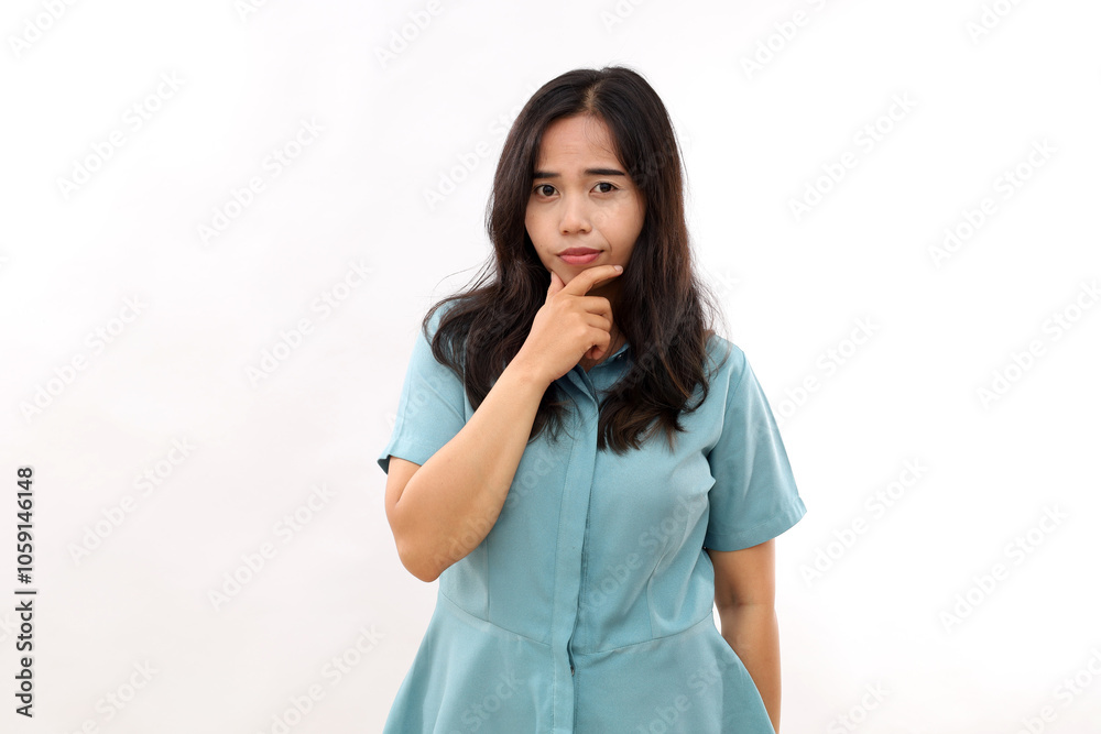Portrait of serious dark haired Asian woman keeps finger on chin looks mysteriously at camera considers something dressed casual shirt isolated over white background. Let me think about it Portrait of serious dark haired Asian woman keeps finger on chin looks mysteriously at camera considers something dressed casual shirt isolated over white background. Let me think about it