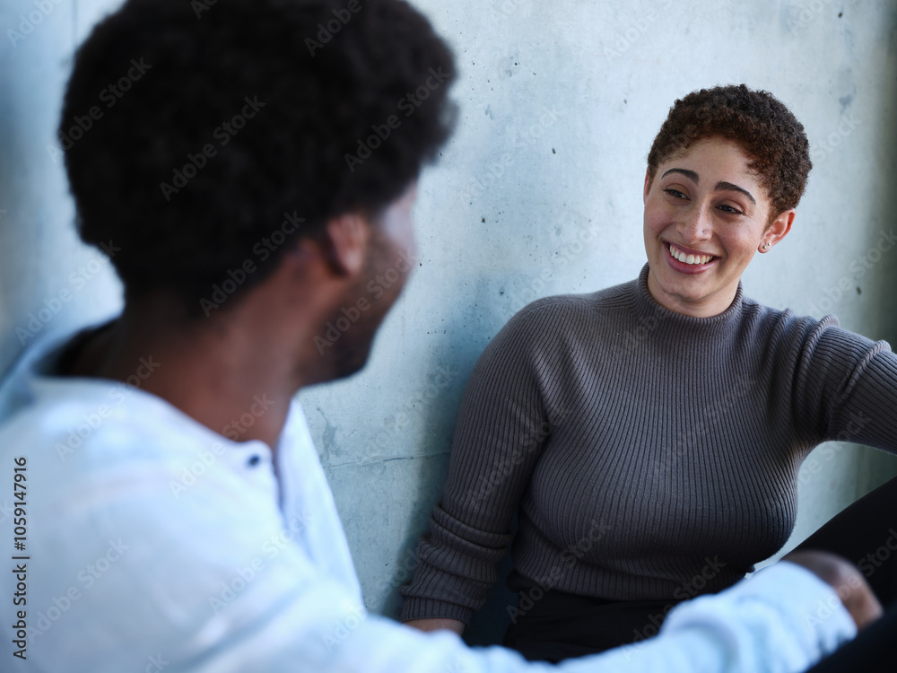 Man and woman sitting against a concrete wall having a conversation Man and woman sitting against a concrete wall having a conversation