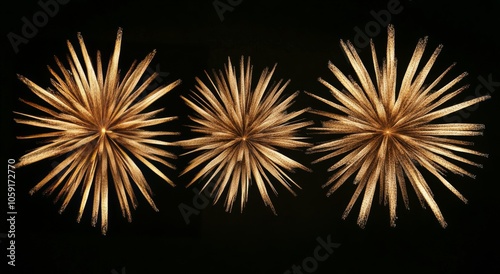 Three golden starburst decorations against a black background for elegant hom...