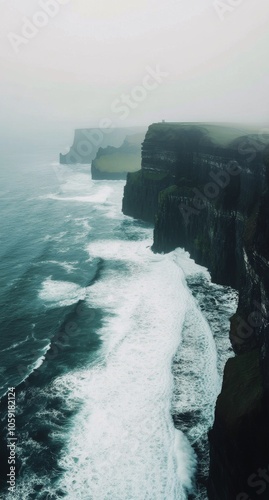 Misty cliffs along the rugged coastline with crashing waves and foggy atmosph...