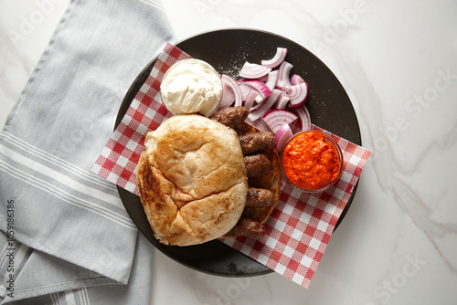 Bread roll with grilled meat, dipping sauce and red onions on the side photo