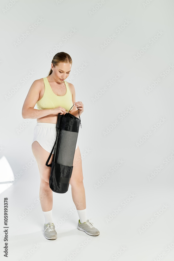 Fototapeta premium A woman wearing a crop top gets ready for her workout in a bright fitness studio, full of energy.