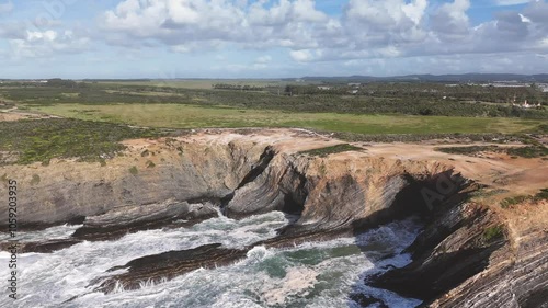 Scenic landscape ocean waves crash on the flysch rocks on a sunny day. Alentejo region, Portugal