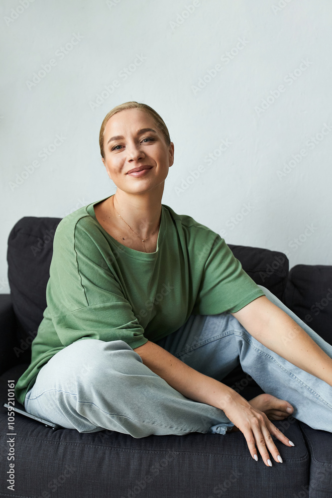 A cheerful woman relaxes comfortably on her couch, exuding warmth and style at home. A cheerful woman relaxes comfortably on her couch, exuding warmth and style at home.