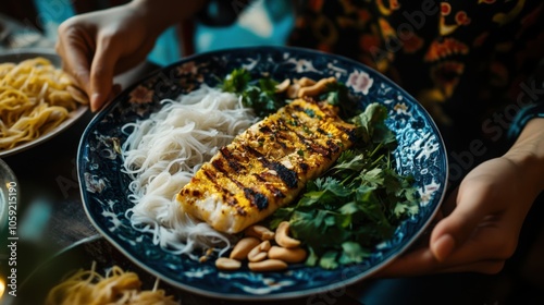 A woman enjoying a plate of cha ca (grilled fish with turmeric and dill) with rice noodles, photo