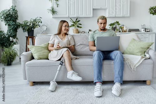 Two friends enjoy their time together in a modern, plant filled living room.