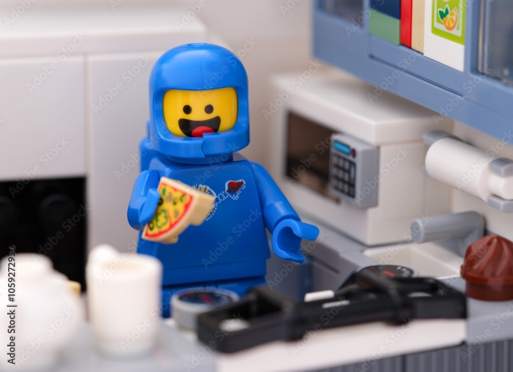 Naklejka premium Tambov, Russian Federation - August 18, 2024 Blue Lego astronaut minfigure eating pizza in his kitchen